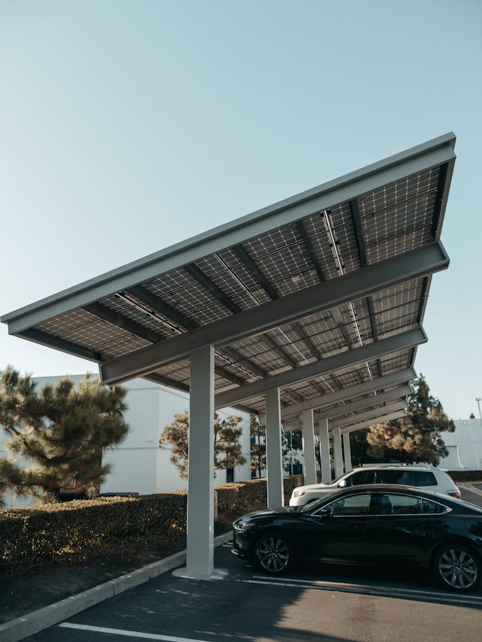 Cars parked under solar panel structures in a modern parking lot utilizing renewable energy.